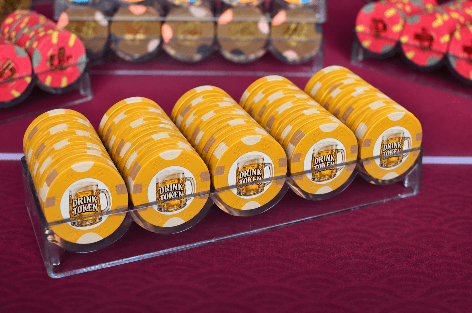 High Score Chips "Drink Token" chips filling a clear acrylic chip rack, with more racked chips in the background