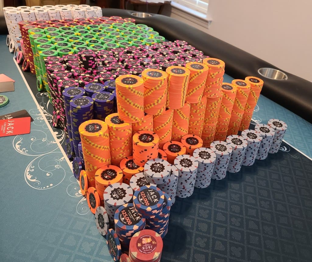 Hundreds of JACK Cincinnati Casino chips stacked by denomination across a poker table